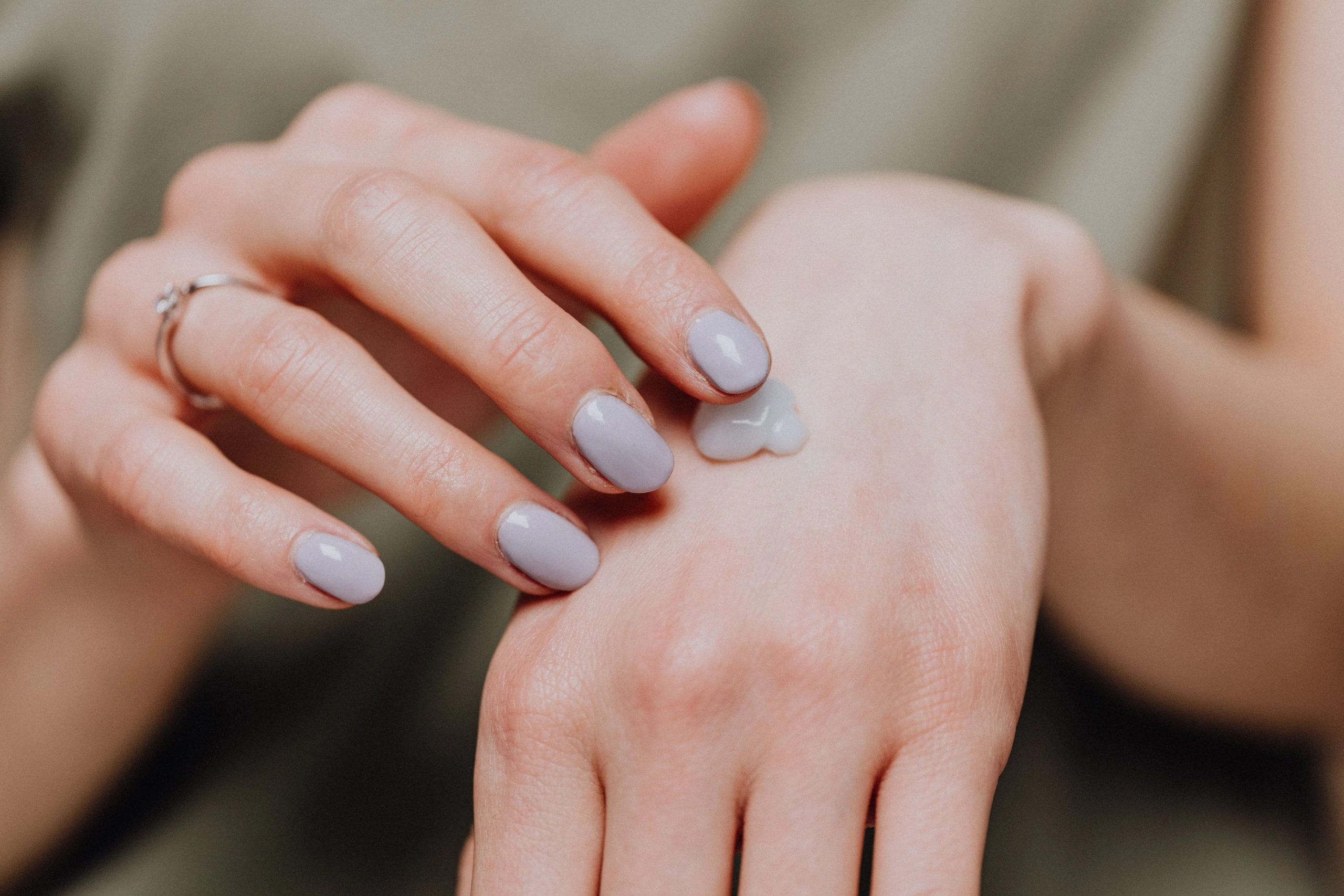 Person applies a small amount of moisturizer to the back of their hand.